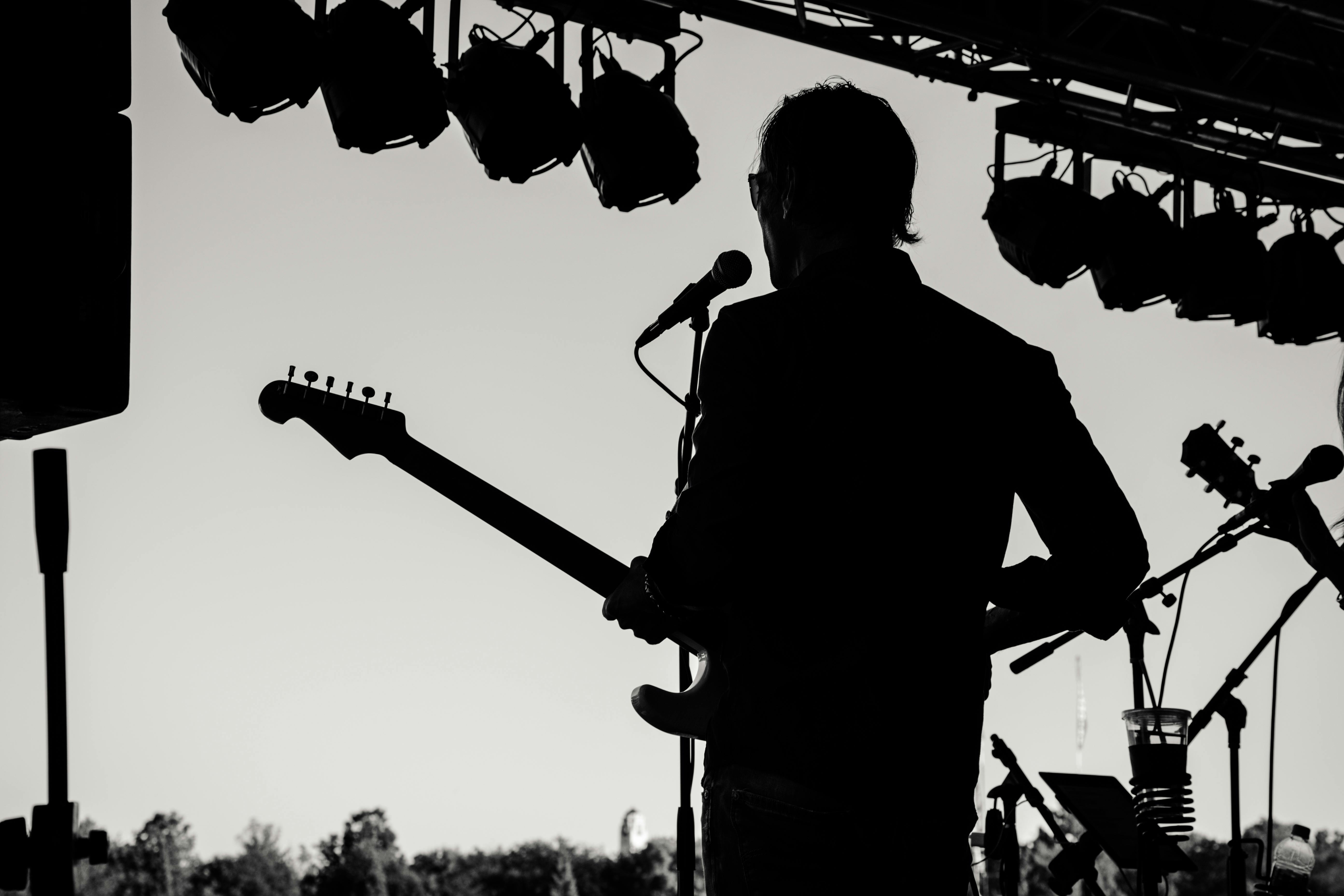 Man met gitaar op podium in zwart wit